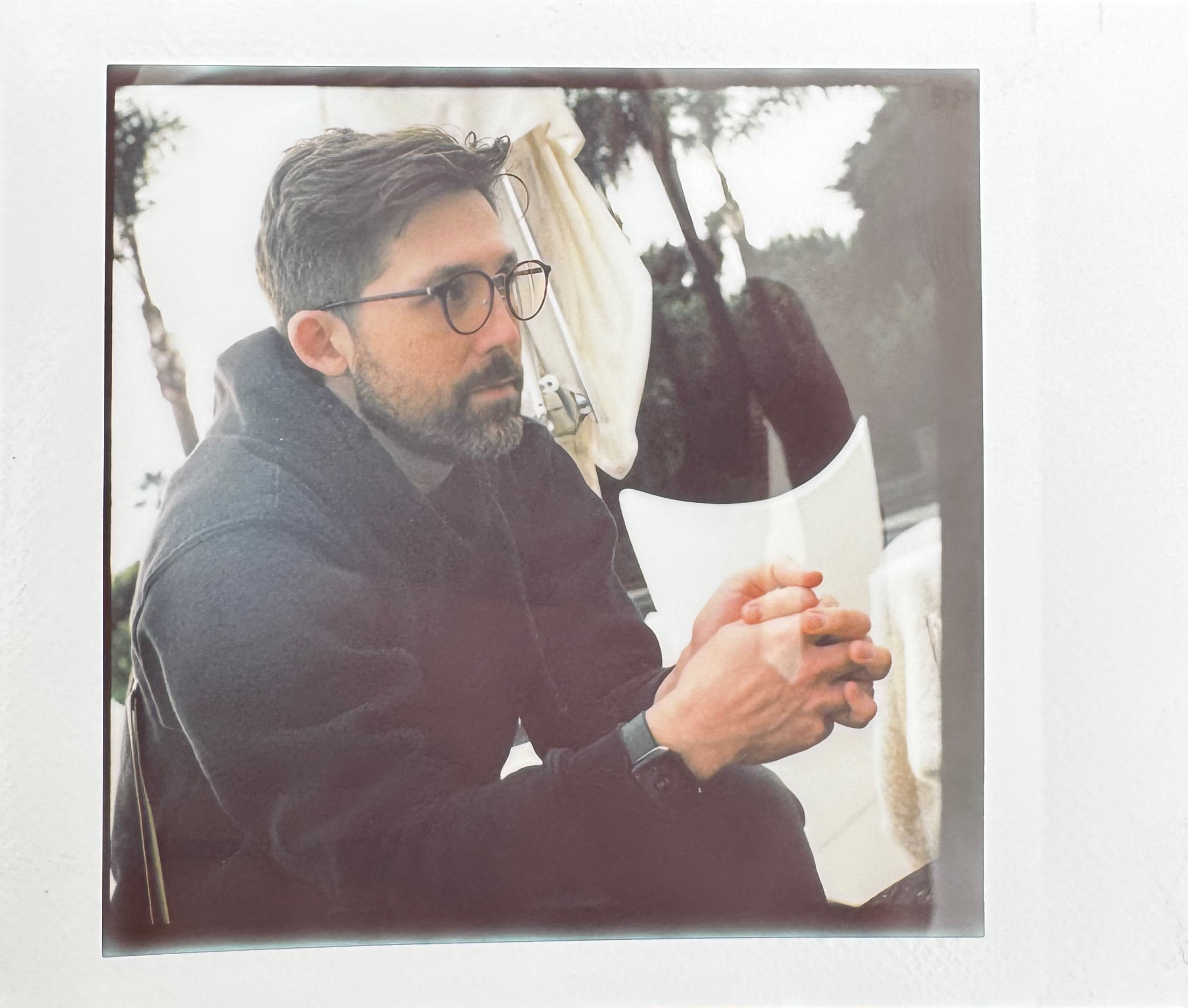 Instant photograph of a man in glasses, with a beard. 