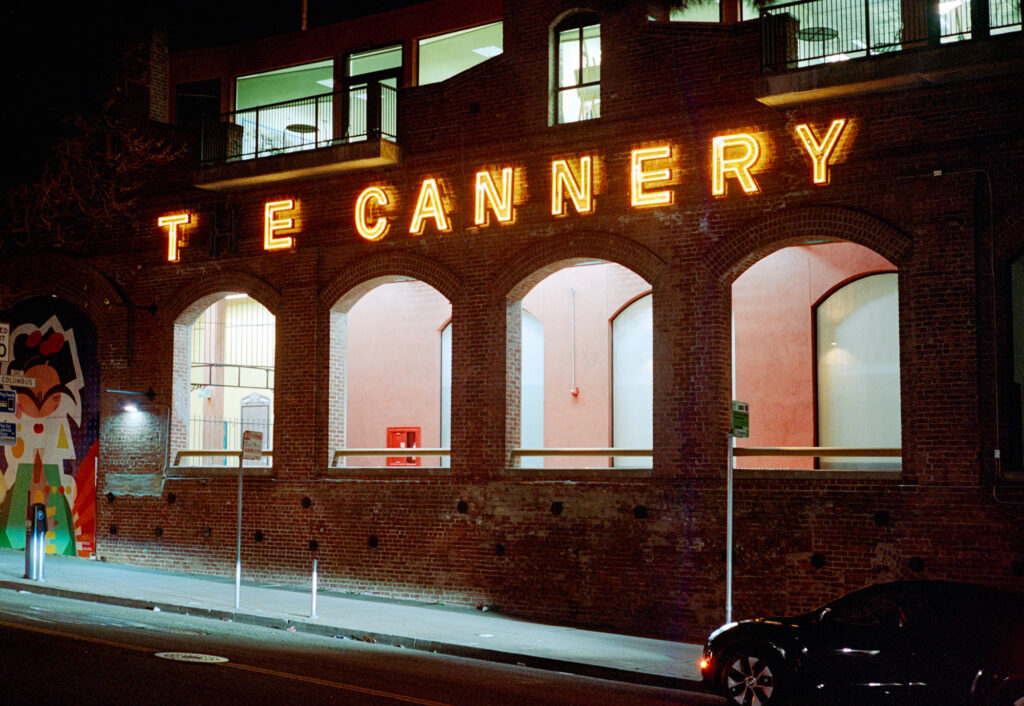 Front of The Cannery at night with the neon sign lit. The "H" in "The" has died.