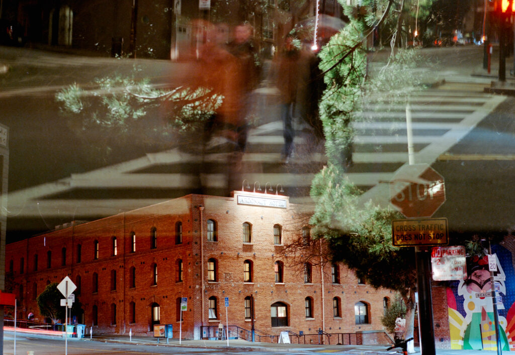 A crosswalk with people, a building, and a tree all layered on top of each other.