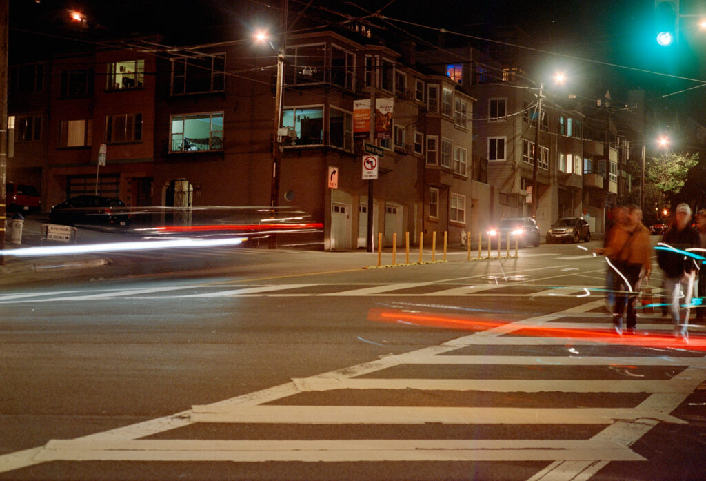 Elongated exposure of a crosswalk at night. Light trails highlight where cars have been.